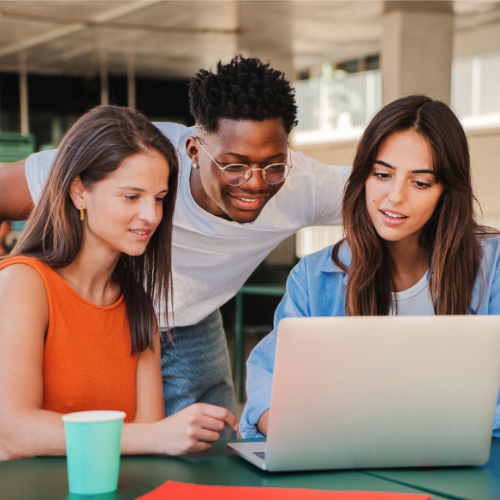 Group of multiracial happy teenage students using laptop, working on university assignment homework project in college library. Meeting of diverse young people looking information on computer volunteer